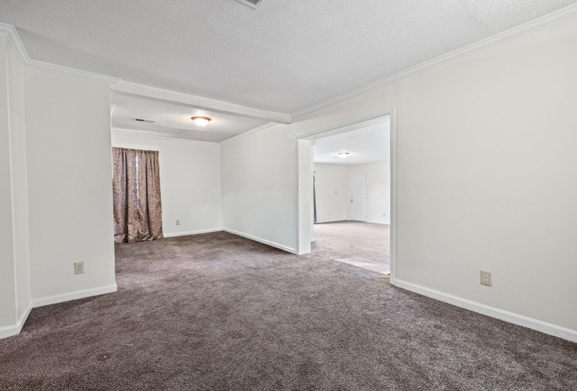Living room featuring ornamental molding, a textured ceiling, and dark colored carpet