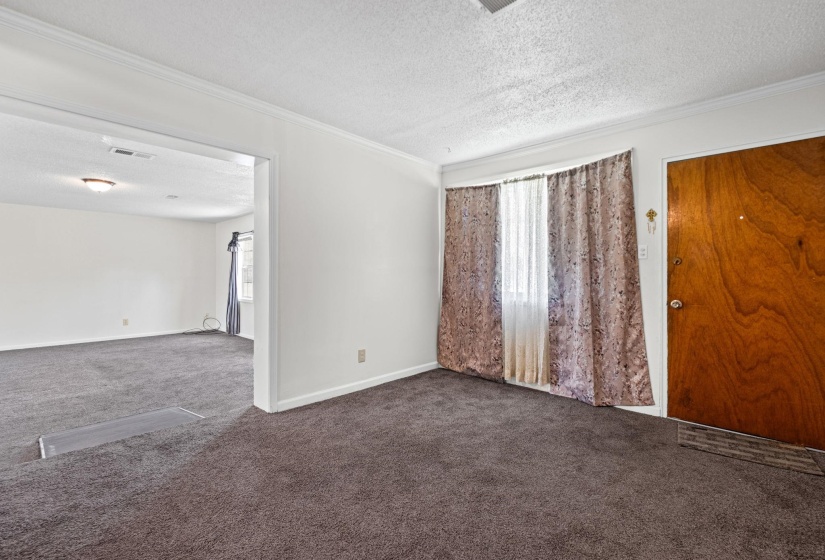 Living room with a textured ceiling and dark colored carpet