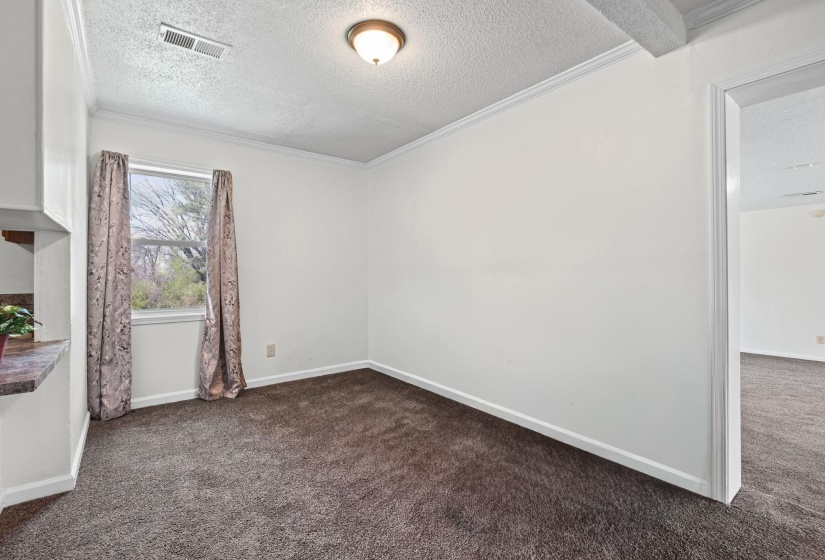Empty room featuring dark colored carpet, a textured ceiling, and crown molding