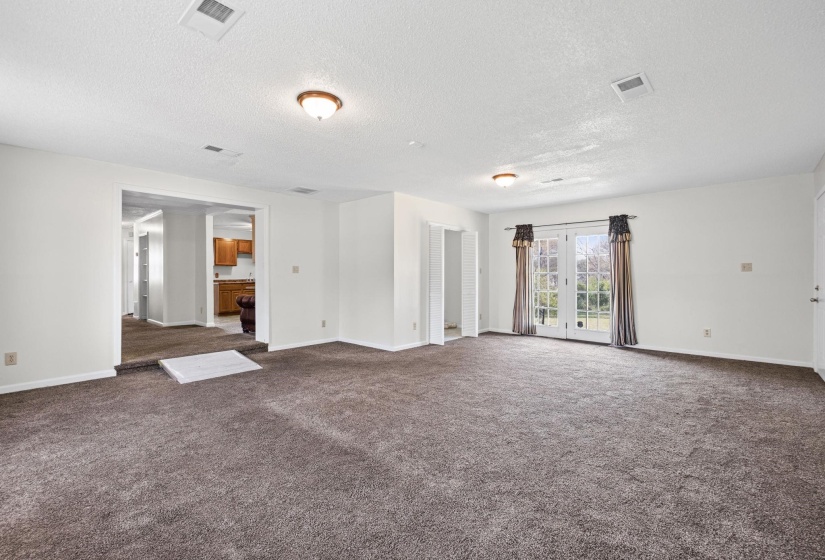 Unfurnished room featuring dark carpet, a textured ceiling, and french doors