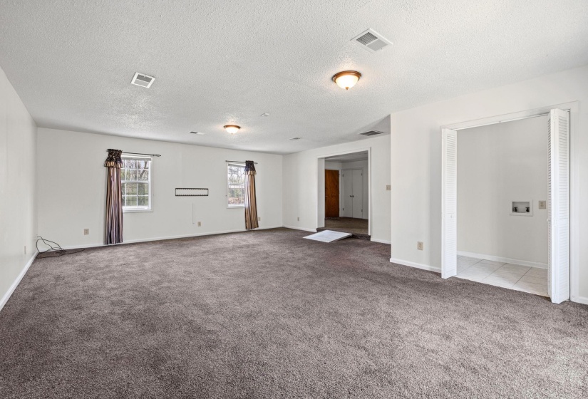 Unfurnished living room featuring carpet flooring and a textured ceiling