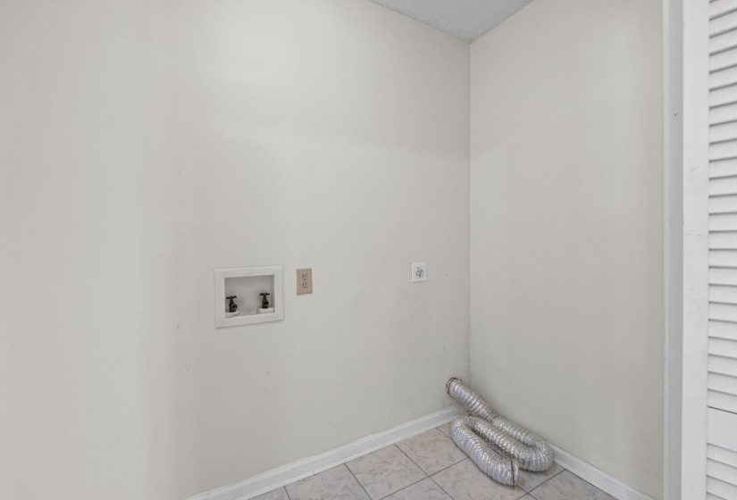 Laundry area with hookup for a washing machine, light tile patterned floors, and electric dryer hookup