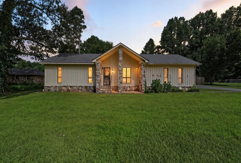 View of front facade featuring a yard, board and batten siding, and stone siding