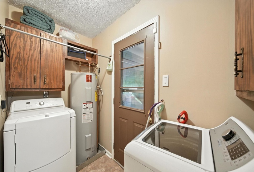 Laundry room with washer and clothes dryer, cabinet space, electric water heater, and a textured ceiling