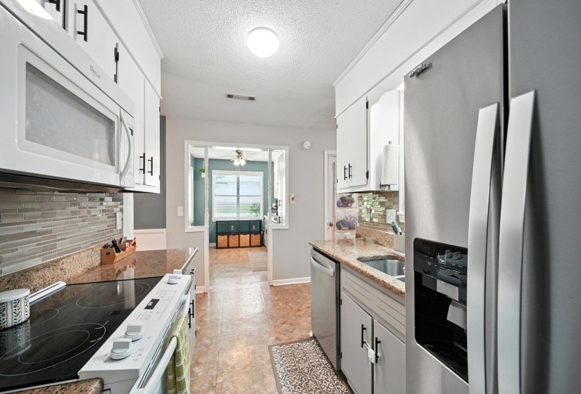 Kitchen with stainless steel appliances, backsplash, a textured ceiling, ceiling fan, and white cabinets