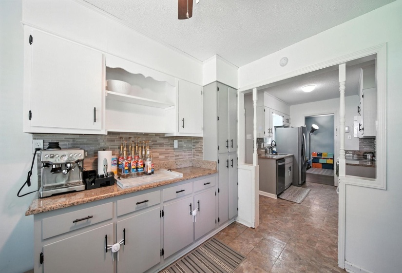 Kitchen featuring tasteful backsplash, stainless steel appliances, open shelves, a textured ceiling, and ornate columns