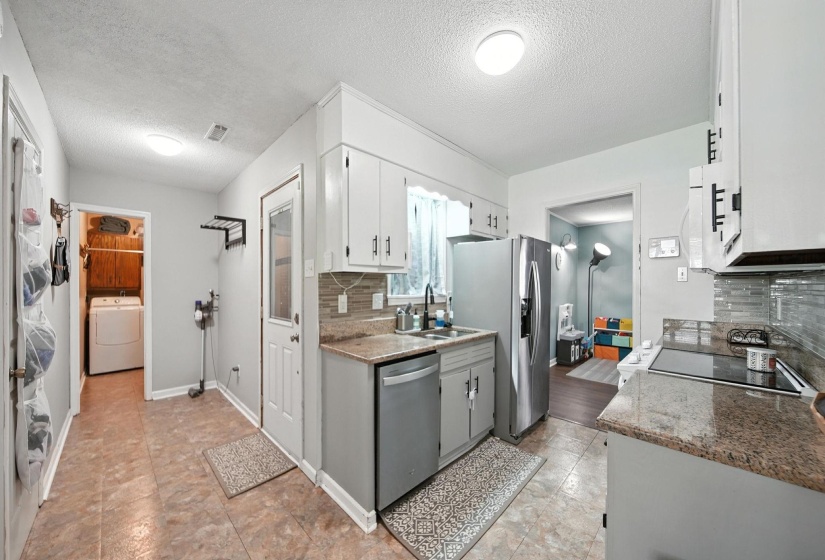 Kitchen with a textured ceiling, tasteful backsplash, stainless steel appliances, and white cabinets