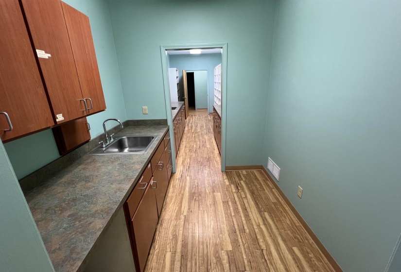 Kitchen featuring a sink, brown cabinets, light wood-style floors, visible vents, and dark countertops