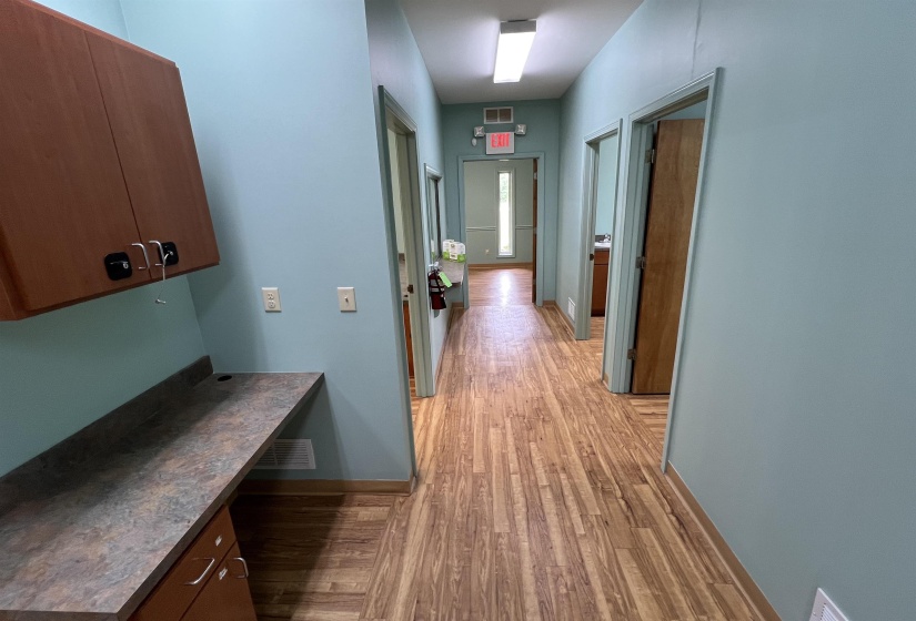 Corridor featuring baseboards, visible vents, and light wood-style floors