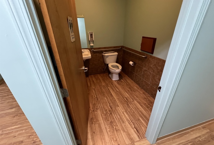 Bathroom with tile walls, wainscoting, wood finished floors, and toilet