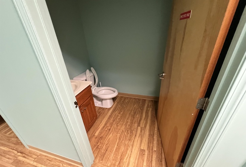 Half bathroom featuring wood finished floors, toilet, vanity, and baseboards
