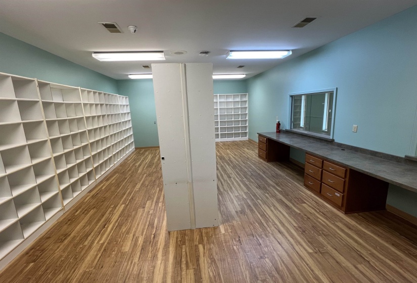 Unfurnished office featuring visible vents, built in study area, and wood finished floors