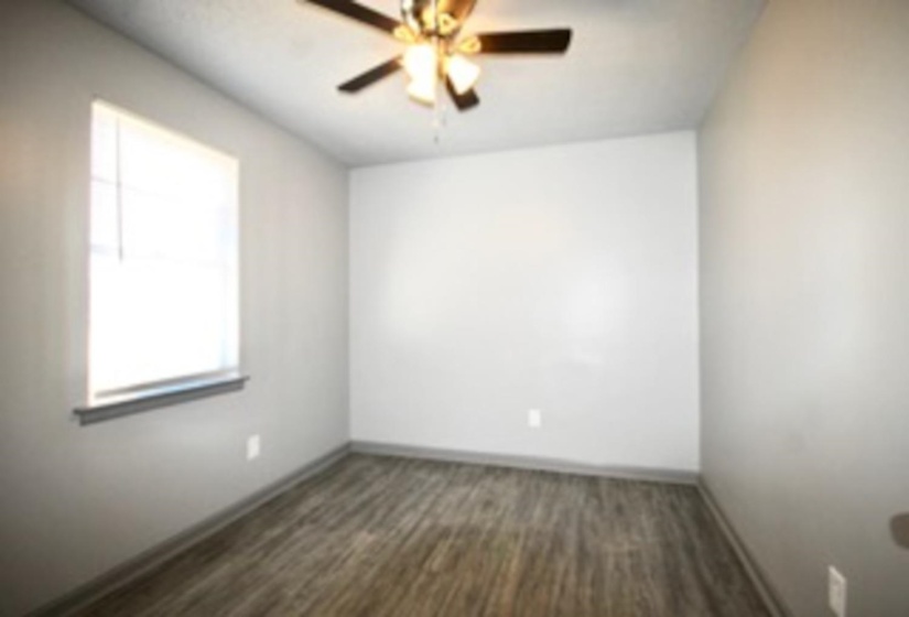 Unfurnished room featuring ceiling fan, baseboards, and dark wood-style floors