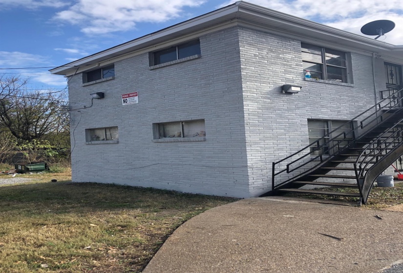 View of property exterior featuring stairway and brick siding