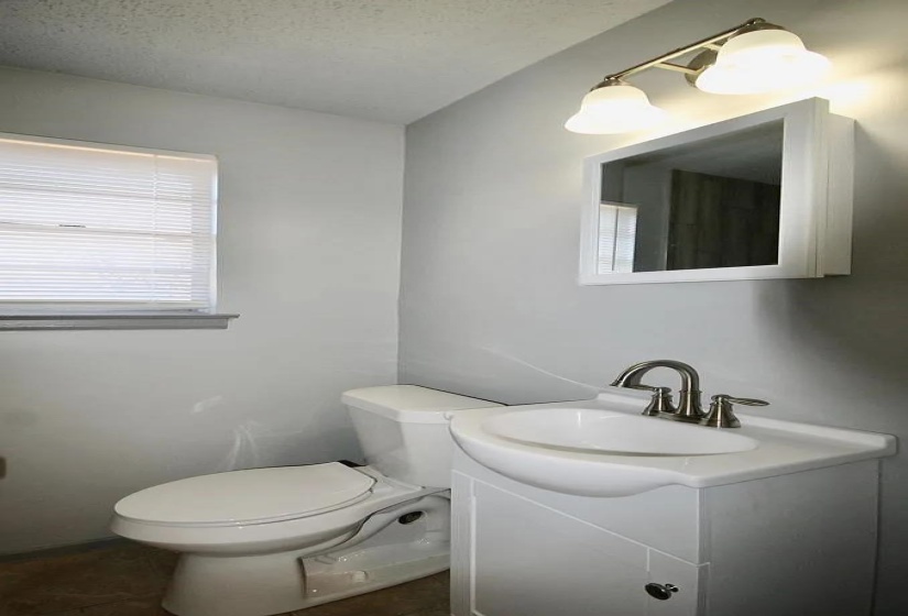 Half bathroom featuring toilet, vanity, and a textured ceiling