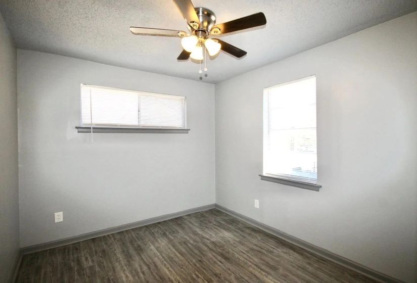 Empty room with dark wood-style flooring, ceiling fan, baseboards, and a textured ceiling