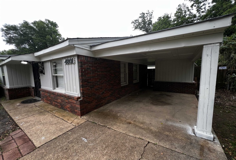 View of home's exterior featuring brick siding, an attached carport, and driveway