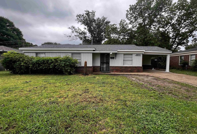 View of front of house featuring brick siding, concrete driveway, a front yard, and a carport