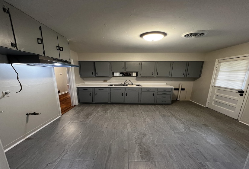 Kitchen featuring gray cabinetry, a sink, baseboards, dark wood-style flooring, and light countertops