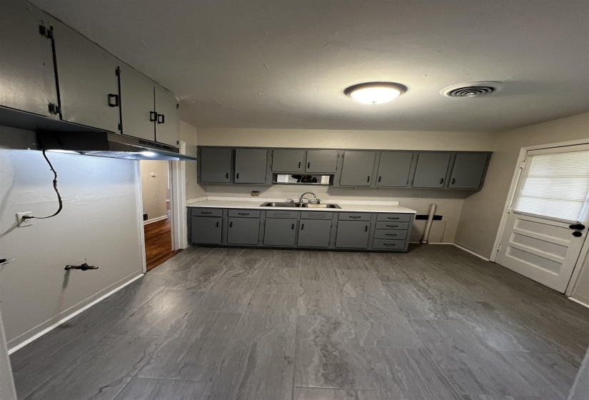 Kitchen featuring gray cabinetry, a sink, baseboards, and light countertops