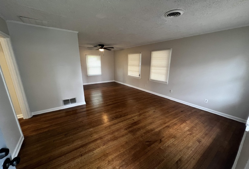 Unfurnished room with dark wood-type flooring, a ceiling fan, a textured ceiling, and baseboards