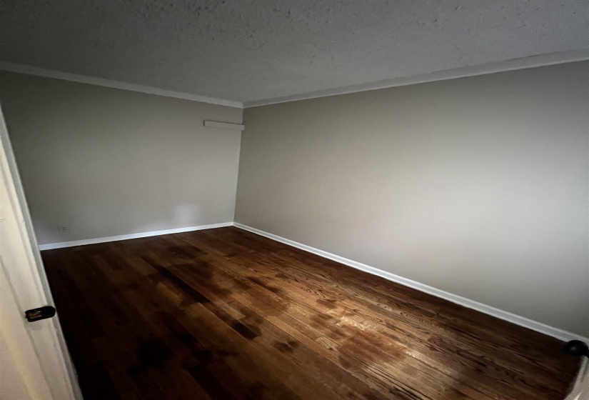 Unfurnished room with crown molding, dark wood-style floors, and baseboards