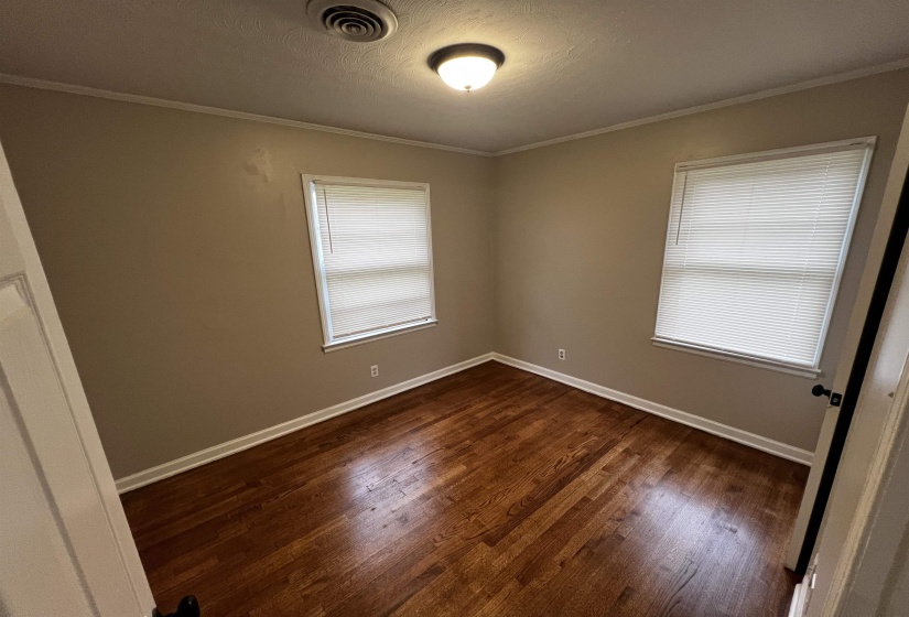 Unfurnished room featuring dark wood-style floors, crown molding, baseboards, and a textured ceiling