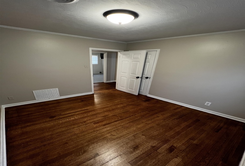 Spare room featuring wood finished floors, baseboards, and ornamental molding