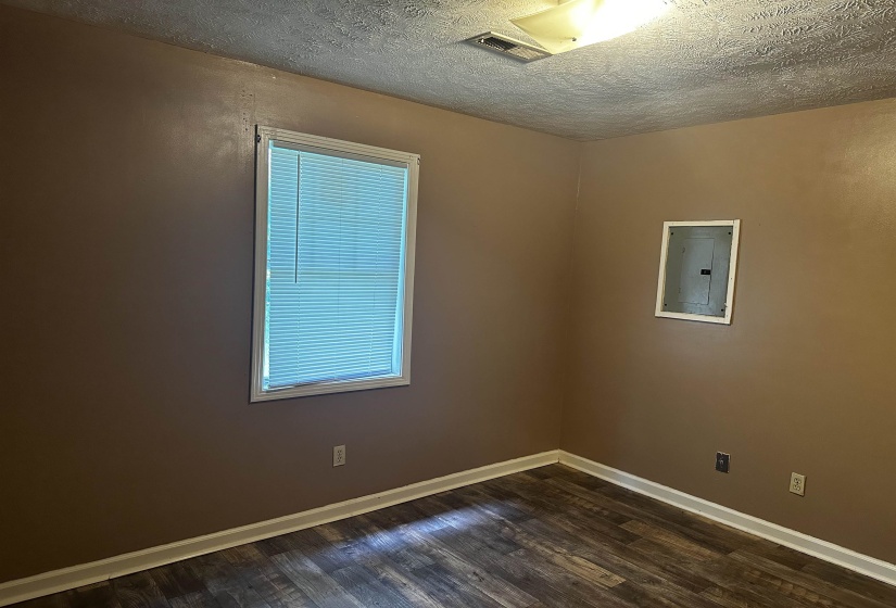 Unfurnished room with a textured ceiling, dark wood-type flooring, and electric panel