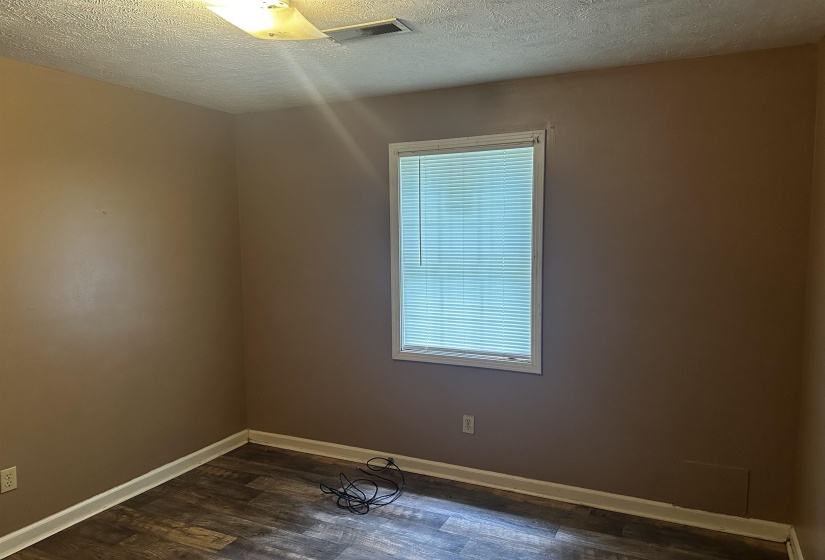 Empty room featuring a textured ceiling and dark wood-type flooring