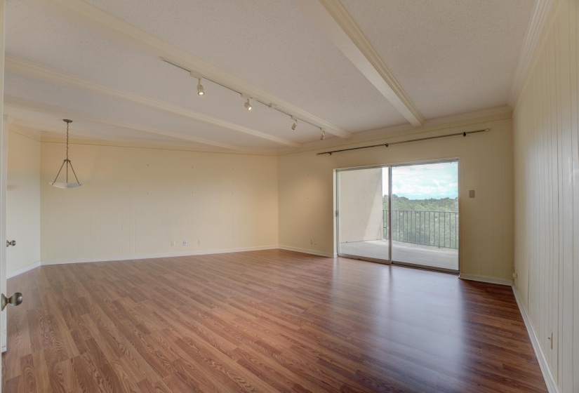 This bright and neutral-toned room offers hardwood floors, a convenient bar, and a kitchenette complete with a refrigerator—perfect as a third bedroom, den, or mother-in-law suite. Double glass doors open to a private balcony.
