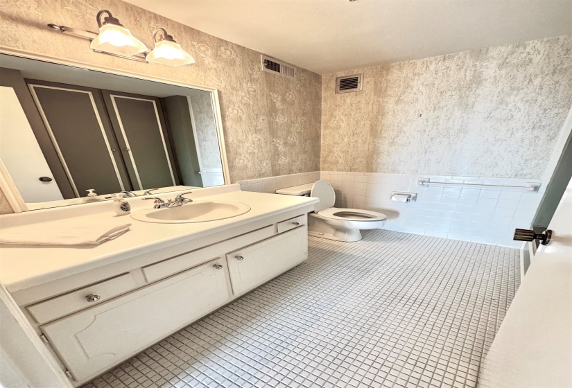 Bathroom featuring vanity, tile patterned flooring, tile walls, wainscoting, and wallpapered walls.
