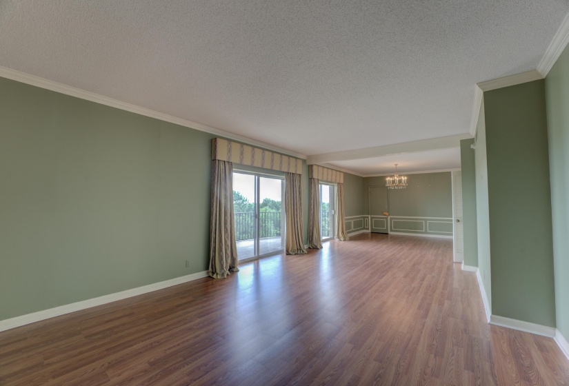 This inviting open-concept living and dining area is bathed in natural light, with gleaming hardwood floors flowing seamlessly between the two spaces. The living room’s airy atmosphere is complemented by two sets of sliding glass doors.