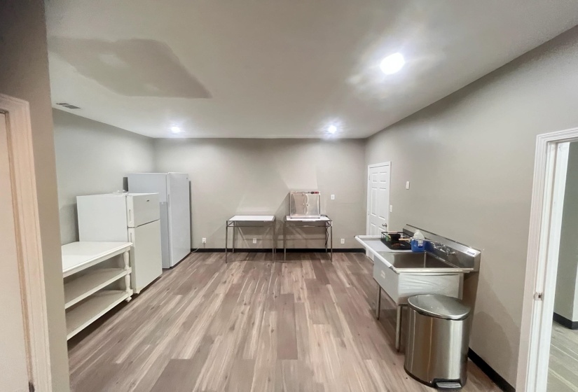 Kitchen with light wood-style flooring, freestanding refrigerator, and light countertops