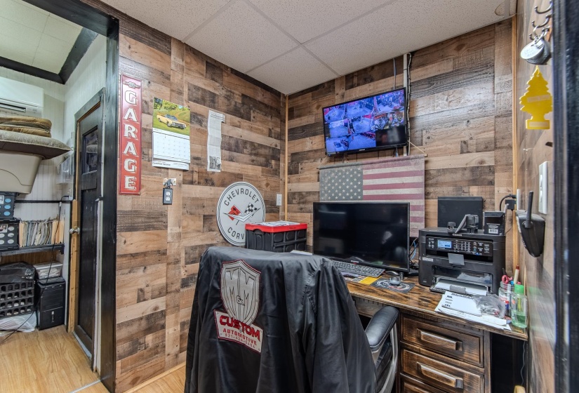 Home office featuring wood walls, a drop ceiling, wood finished floors, and a wall unit AC