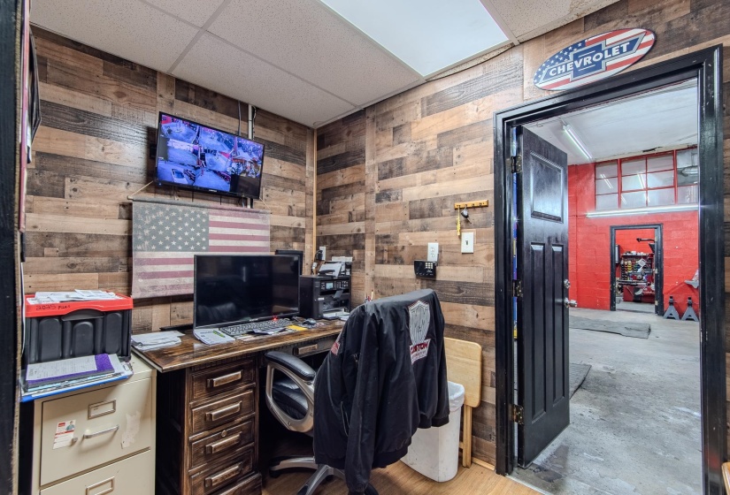 Office with a drop ceiling, wood walls, and concrete flooring