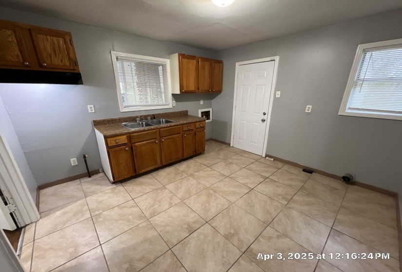 Kitchen featuring dark countertops, brown cabinetry, light tile patterned floors, and plenty of natural light