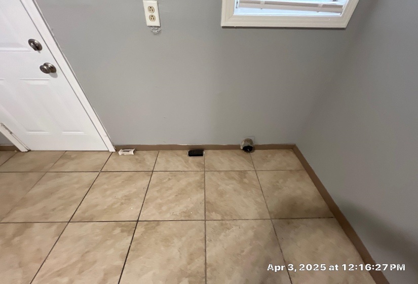 Laundry area with light tile patterned flooring and baseboards