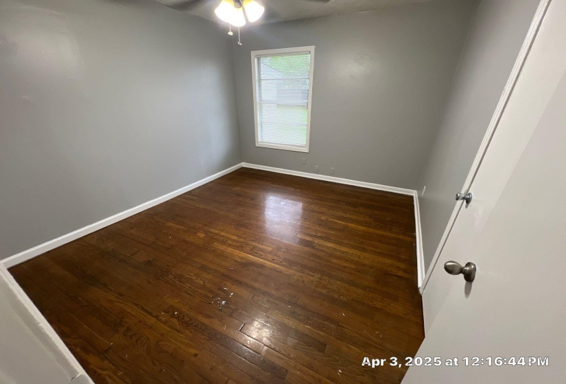 Empty room featuring dark wood-style floors and baseboards