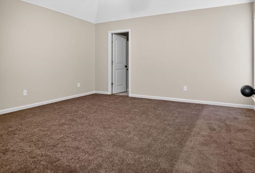 Empty room featuring dark carpet and baseboards