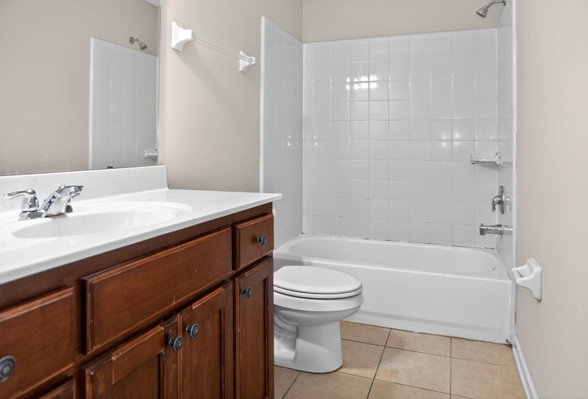 Bathroom featuring shower / tub combination, light tile patterned flooring, and vanity