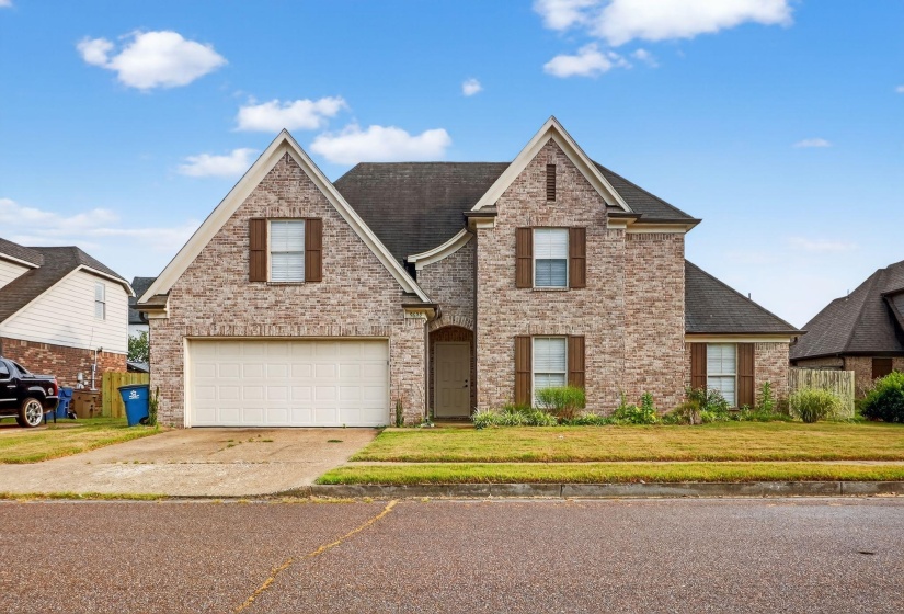 Traditional home with concrete driveway, an attached garage, brick siding, and roof with shingles