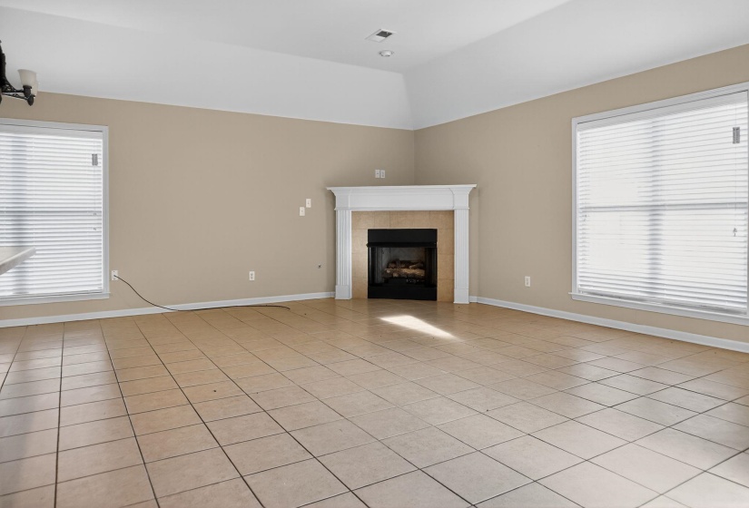 Unfurnished living room with light tile patterned floors, a fireplace, and lofted ceiling