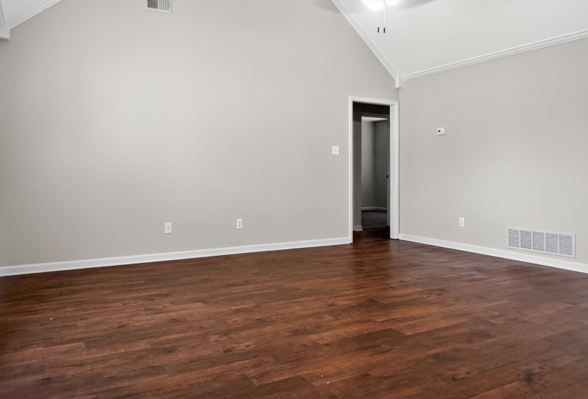 Unfurnished room with dark wood-style flooring, lofted ceiling, crown molding, and a ceiling fan