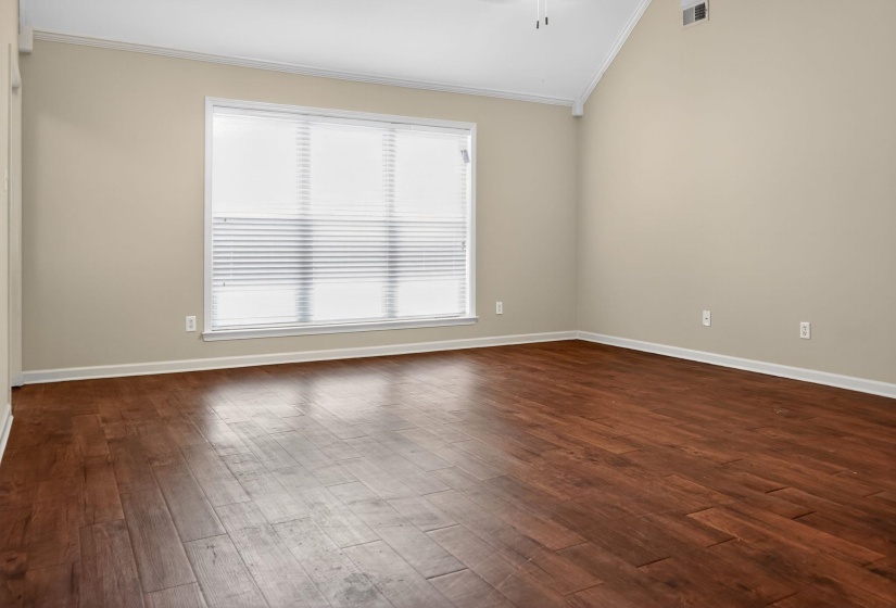 Spare room featuring dark wood-type flooring, crown molding, and vaulted ceiling