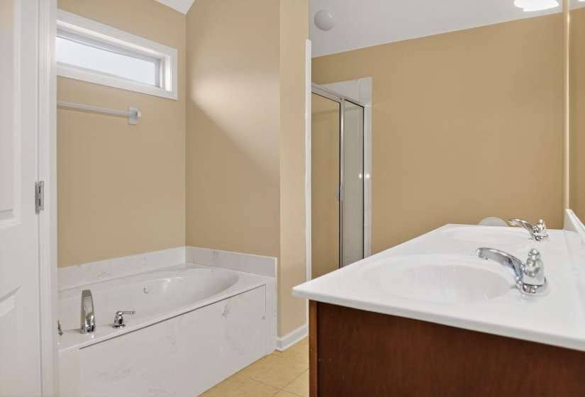 Bathroom with a shower stall, a garden tub, light tile patterned floors, and double vanity