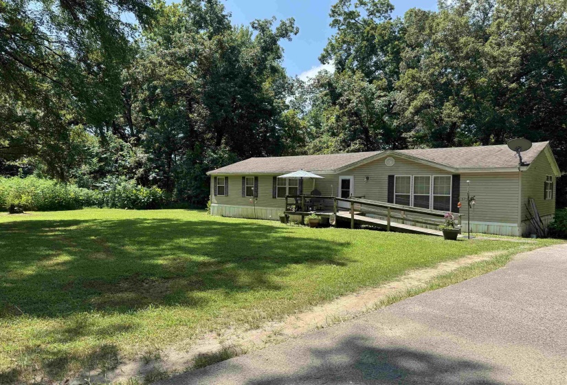 Manufactured / mobile home featuring a front yard, view of wooded area, and a wooden deck