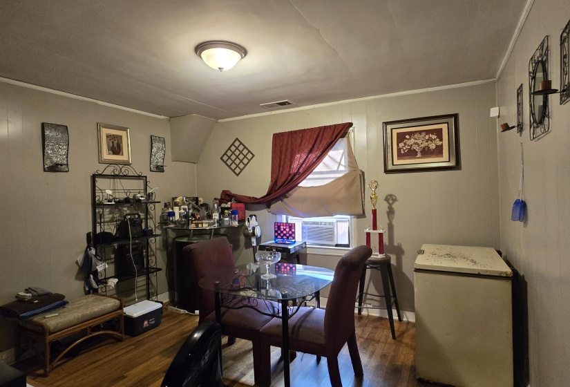Dining room featuring crown molding, dark wood finished floors, and wood walls
