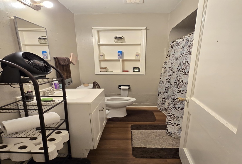 Bathroom with dark wood-type flooring, vanity, and a shower with shower curtain