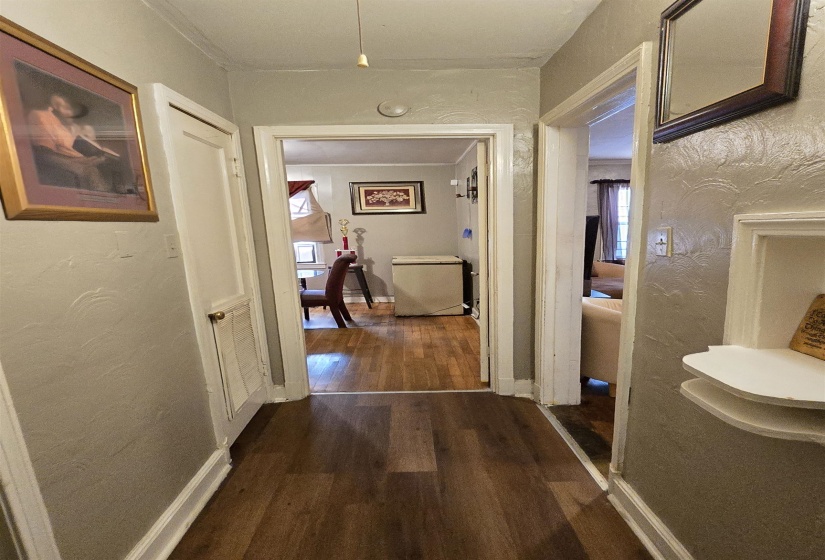 Hall featuring a textured wall and dark wood-type flooring